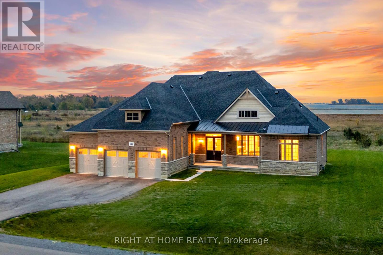 Front exterior at twilight — triple garage, lake views