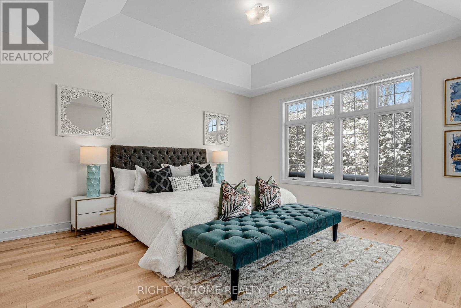 Primary bedroom — tray ceiling, hardwood, large windows
